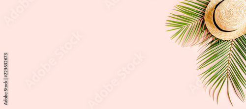 Tropical palm leaves and hat on pink background with more space for text. Flat lay, top view minimal concept.