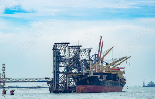 Bulk Vessel alongside at sea port terminal by loading with conveyor, general bulk vessel loading bulk cargo by shiploader.