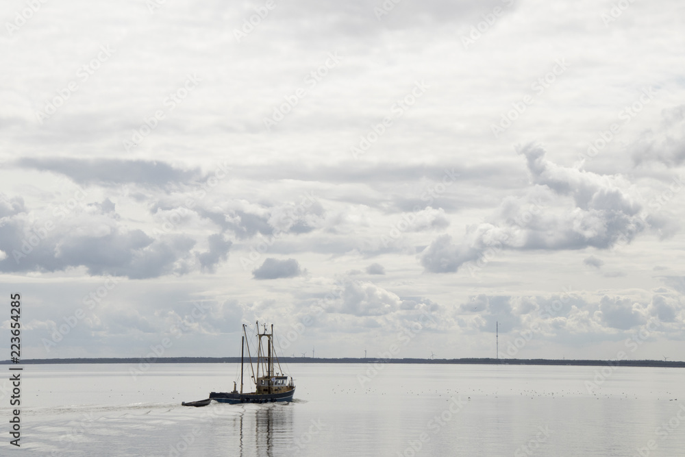 Fishing boat is emptying the nets, placed along the Aflsluitdijk in a calm peacfull IJsslemeer Fishing boat is emptying the nets, placed along the Aflsluitdijk in a calm peacfull IJsslemeer