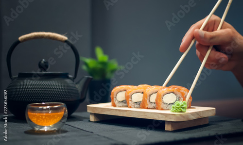 Philadelphia roll on wooden plate and fruit tea