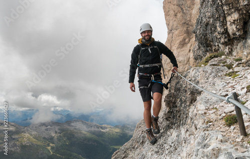 young male mountain climber on a steep and exposed Via Ferrata in Alta Badia in the South Tyrol in the Italian Dolomites © makasana photo
