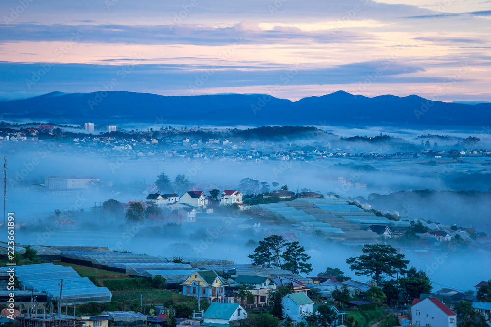 wonderful landscape of Da Lat city, early morning fog covering the city, far away is the green mountains, mist covered the greenhouse under the morning sun