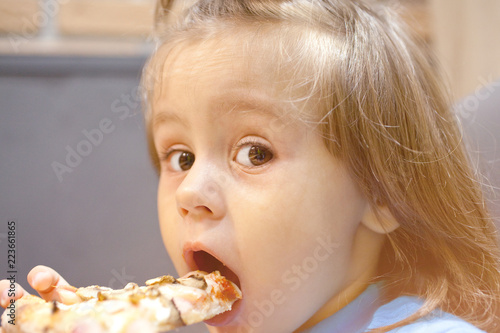 little girl is eating pizza in a cafe