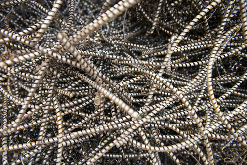 Background of tangled twisted industrial scrap metal waste, spiral machine shavings and filings