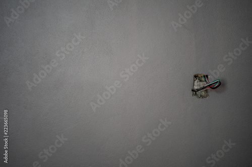 Several exposed copper wires protruding from a beige wall. © Danupol