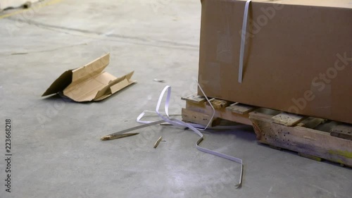 A warehouse worker trips on debris beside a pallet in a warehouse
