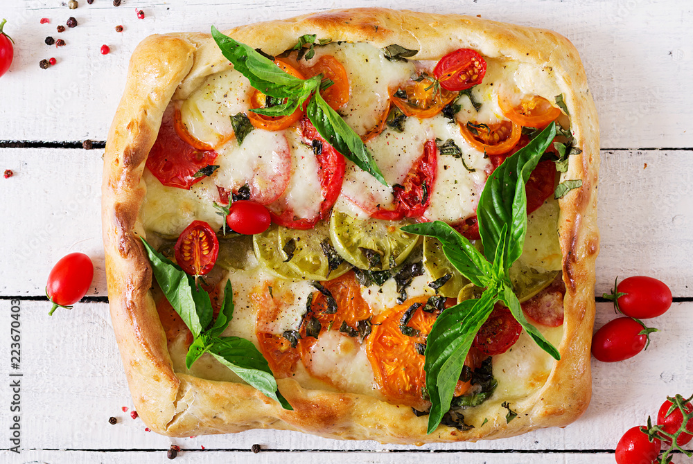 Mozzarella, tomatoes, basil savory pie on a white wooden background. Delicious food, appetizer in a mediterranean style. Top view. Flat lay Mozzarella, tomatoes, basil savory pie on a white wooden background. Delicious food, appetizer in a mediterranean style. Top view. Flat lay