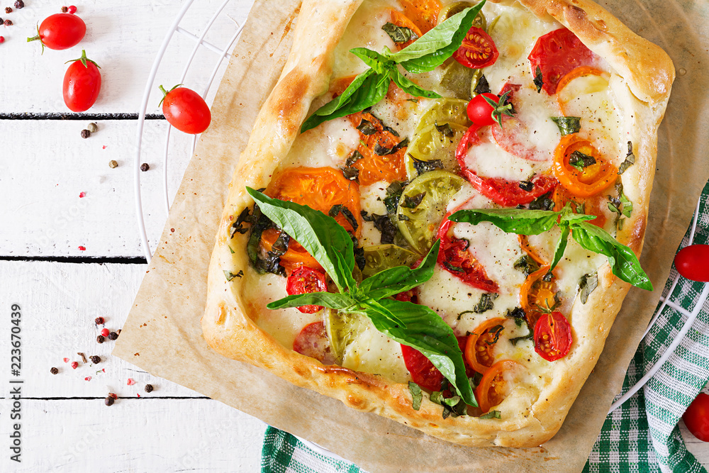 Mozzarella, tomatoes, basil savory pie on a white wooden background. Delicious food, appetizer in a mediterranean style. Top view. Flat lay Mozzarella, tomatoes, basil savory pie on a white wooden background. Delicious food, appetizer in a mediterranean style. Top view. Flat lay