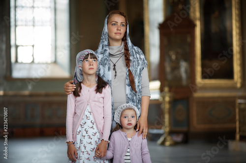 Young mother and her little blond Caucasian daughter with candles in Orthodox Russian Church