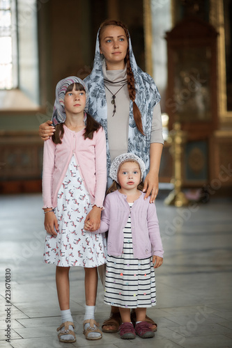 Young mother and her little blond Caucasian daughter with candles in Orthodox Russian Church