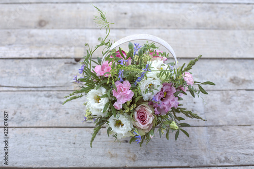 Flowers in a white basket on a wooden background