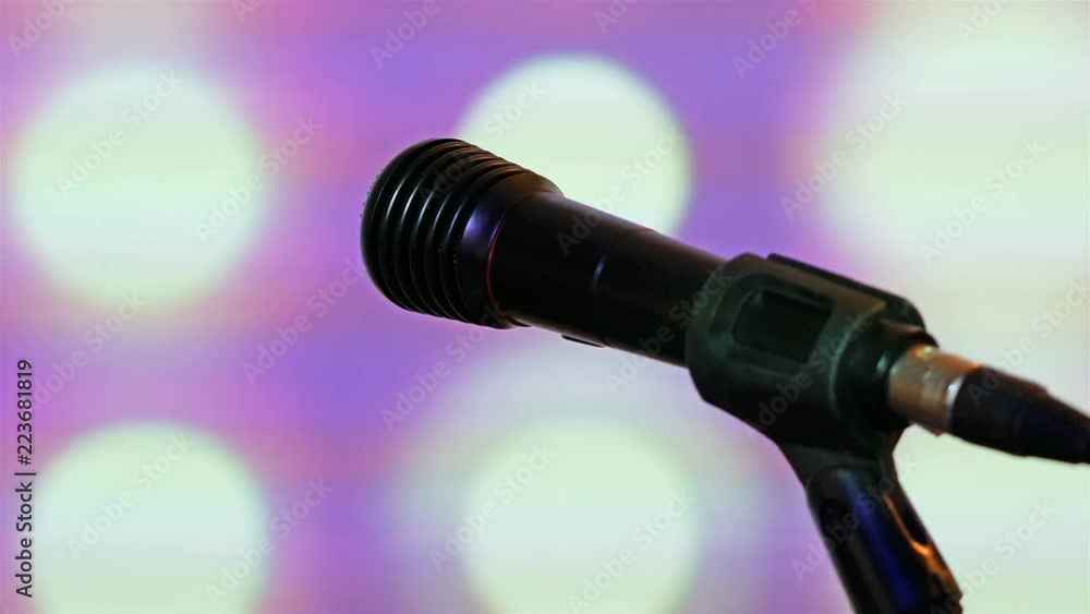 Black wired microphone on stand and club lights at background Black wired microphone on stand and club lights at background