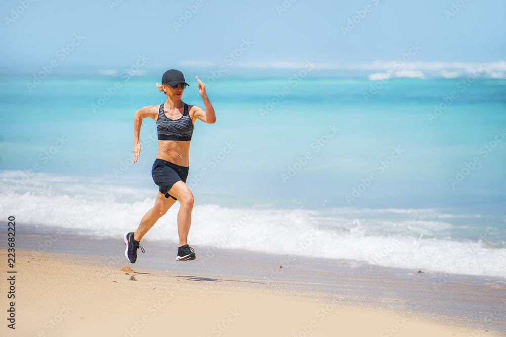 young happy and attractive sport runner woman doing running workout sprinting on tropical paradise beach showing fit and athletic body in wellness fitness concept