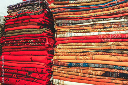 A pile of neatly folded, beautiful hand woven berber rugs for sale in Fez, Morocco