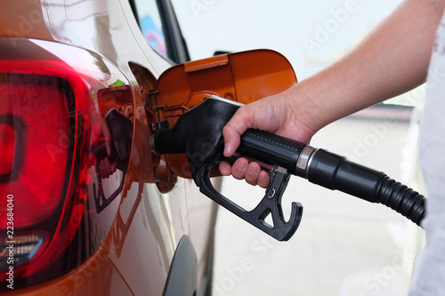 Obraz na plátne Man fills up his orange car with a gasoline at gas station