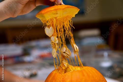 Hand of a Man Lifts the Top Cap Off of a Cut Pumpkin Ready to Scoop Out and Carve