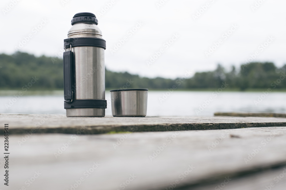 Metal thermos on the old wooden bridge, close-up Metal thermos on the old wooden bridge, close-up