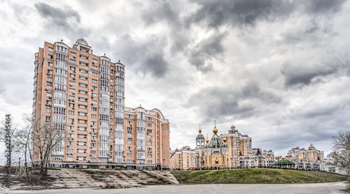 Modern buildings, and the Birth of Christ Church in the Obolon district of Kiev, Ukraine, near the Dnieper River, under a stormy and cloudy sky