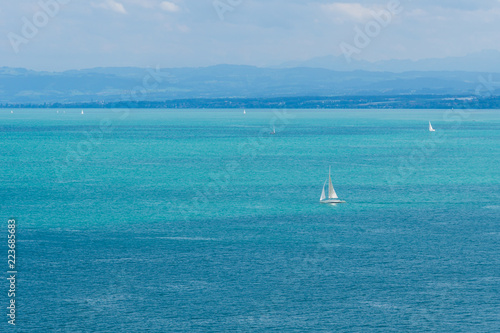 Sailboats on blue water with mountains behind
