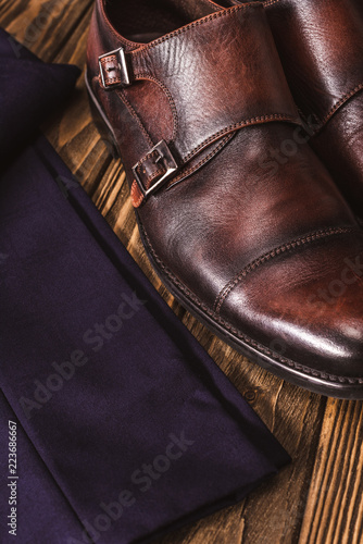 close up view of masculine leather shoes and pants on wooden tabletop