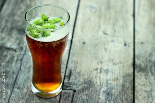 A glass of cold beer with fresh fragrant hops wood textere photo
