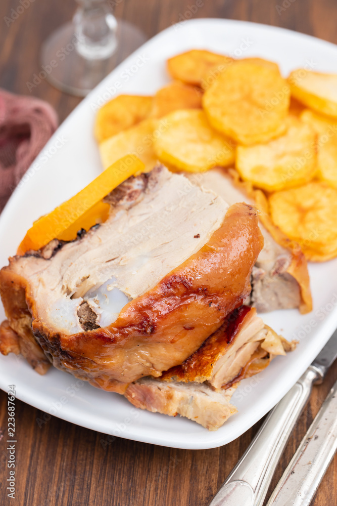 roasted piglet with potato chips and orange on white plate roasted piglet with potato chips and orange on white plate
