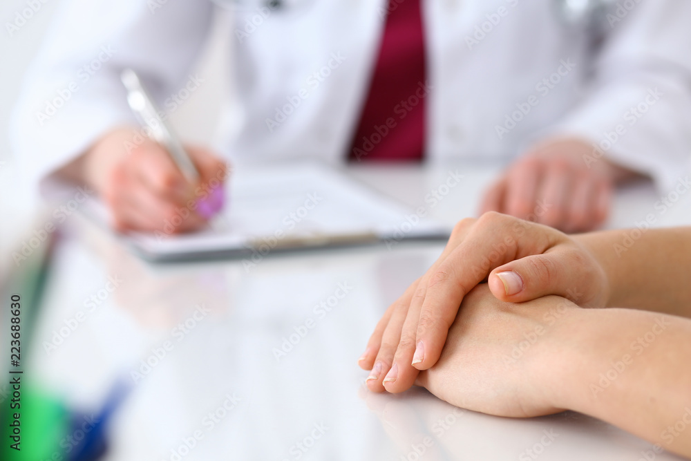 Doctor woman consulting patient while filling up an application form at the desk in hospital. Just hands close-up. Medicine and health care concept