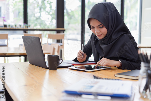 Muslim business people wearing black hijab,working in coffee shop.