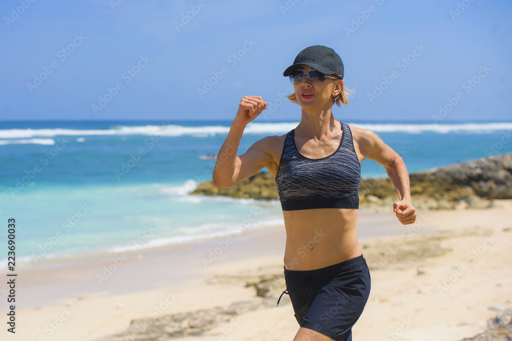 young happy and attractive sport runner woman doing running workout jogging on tropical paradise beach showing fit and athletic body in wellness fitness