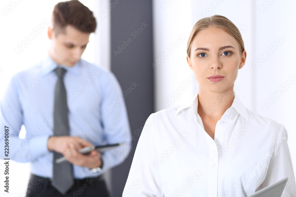 Beautiful blonde businesswoman standing straight in a brightly lit office at the background of colleagues or partners. Business concept Beautiful blonde businesswoman standing straight in a brightly lit office at the background of colleagues or partners. Business concept