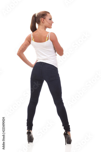Full length portrait woman in a white tank top and jeans.