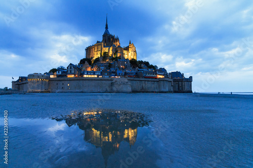 Beautiful view of historic landmark Le Mont Saint-Michel in Normandy, France, a famous UNESCO world heritage site and tourist attraction, at twilight in the blue hour after sunset