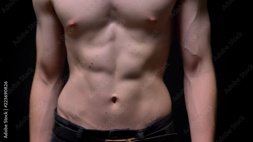 sporty topless caucasian man walking in camera and demonstrating his fit body on dark background in studio sporty topless caucasian man walking in camera and demonstrating his fit body on dark background in studio