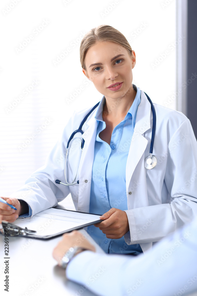Doctor and patient in hospital. Beautiful blonde physician consulting business man about his health. Medicine concept Doctor and patient in hospital. Beautiful blonde physician consulting business man about his health. Medicine concept