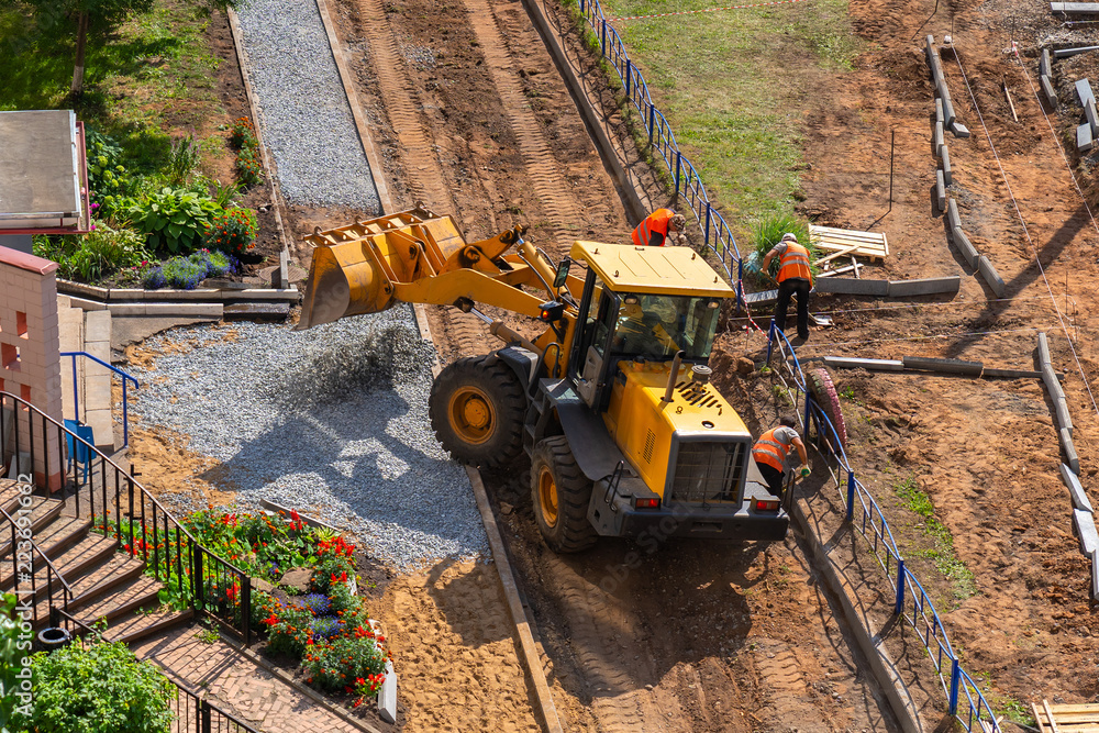 a yellow loader is unloading gravel for making pavement a yellow loader is unloading gravel for making pavement