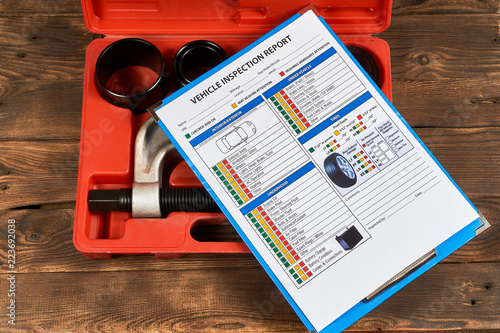 Vehicle vehicle inspection report form against the background of automotive tools on the wooden background. Close up.