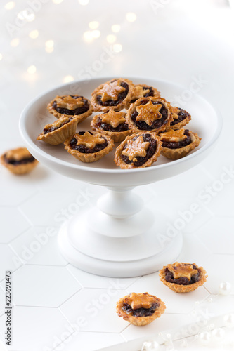 Christmas mince pies on a white stand with festive lights at thhe background photo