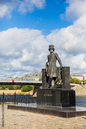 Monument to Russian poet Alexander Pushkin on the embankment in Tver, Russia. Volga river embankment. Autumn day. Picturesque landscape. Old Volga road bridge in the background.