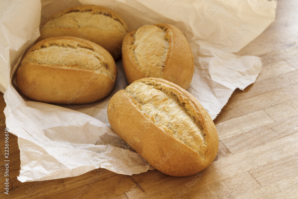 bread rolls or buns for breakfast fresh from the bakery in a white paper  bag on a wooden table Stock-Foto | Adobe Stock