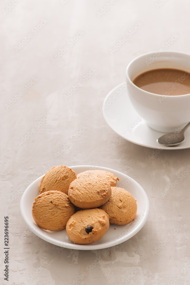 Coffee. White porcelain cup of freshly brewed coffee top view close-up arranged with biscuits, spoon and plate on light background Coffee. White porcelain cup of freshly brewed coffee top view close-up arranged with biscuits, spoon and plate on light background