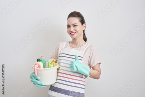 Happy smiling housewife holding cleaning tools and showing thumbs up isolated on white background. Cleaning service, housekeeping concept