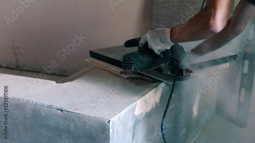 Builder cuts the board with a circular saw on the house construction photo