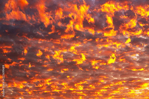 Burning clouds against the background of the setting sun. Photo of a fiery sky at sunset. Fiery clouds against the sky. Suitable for any design.