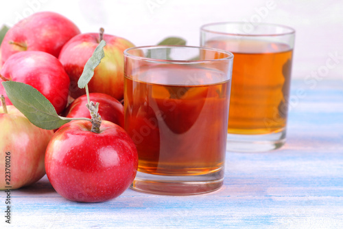 Apple juice in a glass with mature fresh red apples on a blue wooden table
