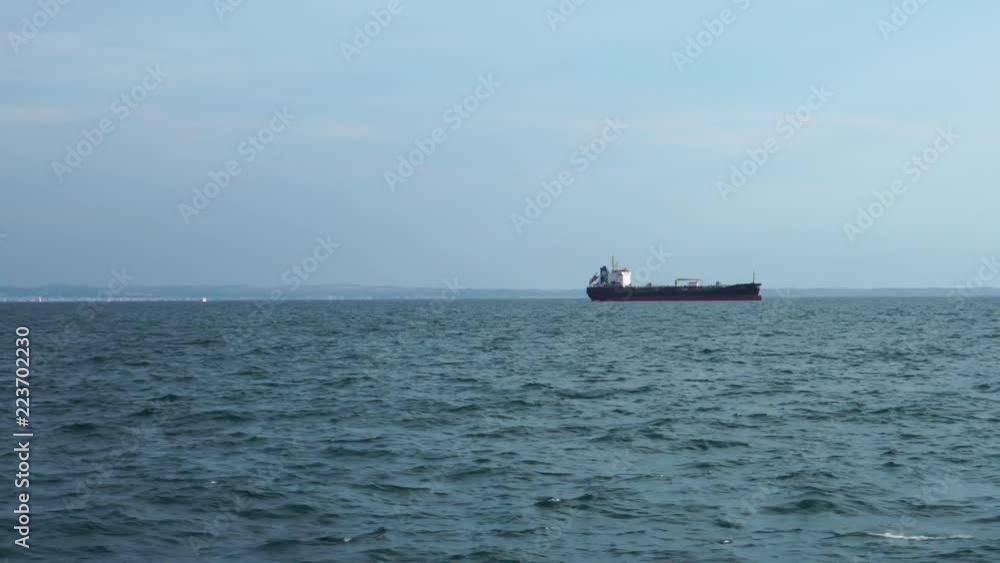 Big freight container cargo ship oil tanker vessel sailing slowly in calm ocean water on cloudy day seascape skyline Big freight container cargo ship oil tanker vessel sailing slowly in calm ocean water on cloudy day seascape skyline