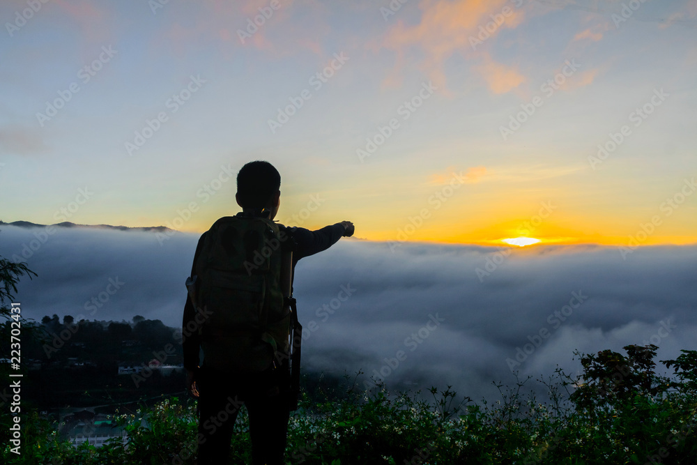 silhouette male  tourist with backpacks stand to the top of mountain and enjoying sunrise. freedom and active lifestyle concept.