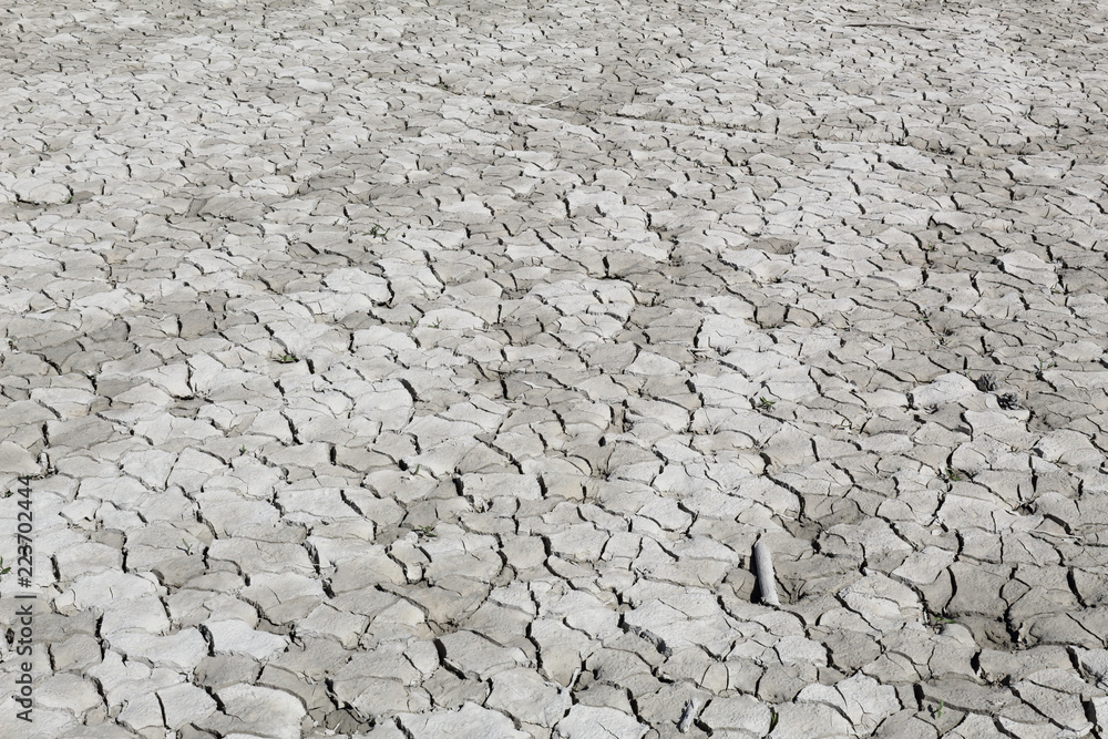 Dry cracked grey clay soil shot in perspective during a hot sunny day in the Mediano artifical lake in the Spanish Aragonese Pyrenees Dry cracked grey clay soil shot in perspective during a hot sunny day in the Mediano artifical lake in the Spanish Aragonese Pyrenees