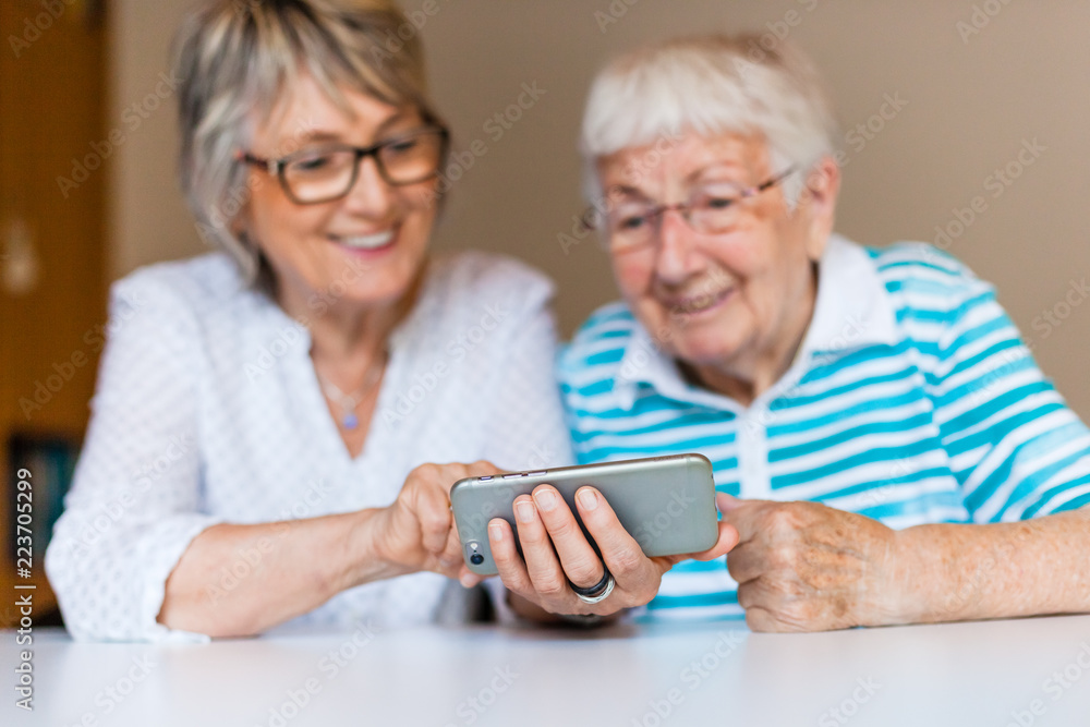 Senior lady using smart phone with her mother Senior lady using smart phone with her mother