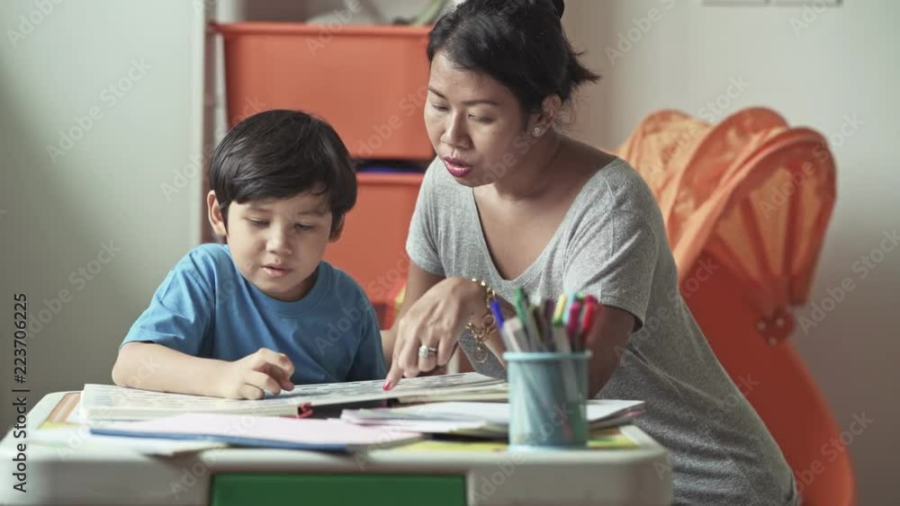 Children homework. Young mixed race boy doing homework in terrace at home. Reading book with his mother. Happy mood. Back to school concept. Children homework. Young mixed race boy doing homework in terrace at home. Reading book with his mother. Happy mood. Back to school concept.
