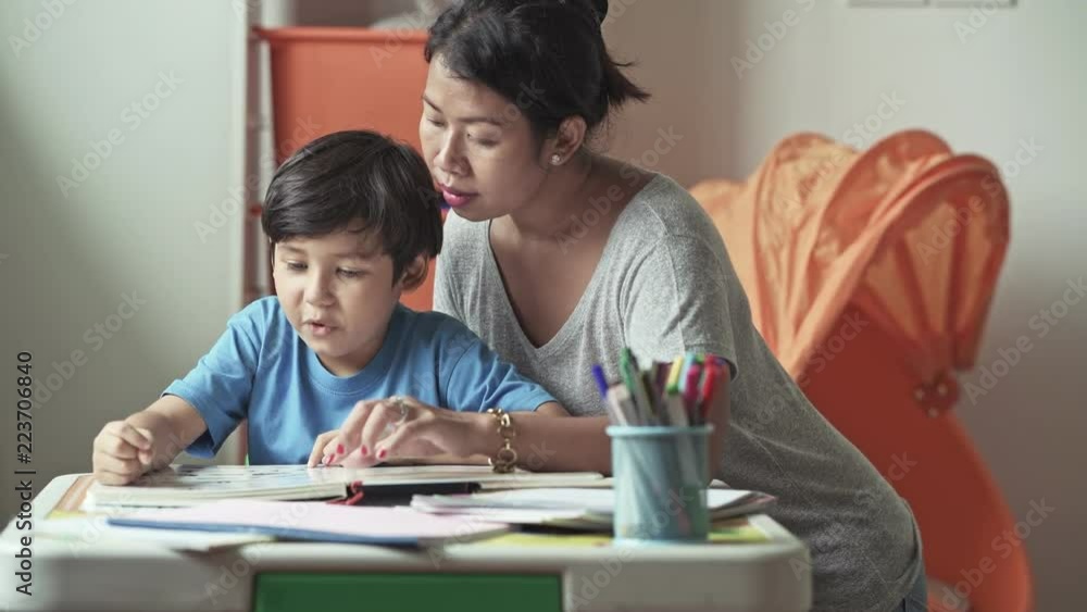 Children homework. Young mixed race boy doing homework in terrace at home. Reading book with his mother. Happy mood. Back to school concept. Children homework. Young mixed race boy doing homework in terrace at home. Reading book with his mother. Happy mood. Back to school concept.